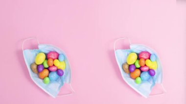 Pastel pembe arka planda Paskalya yumurtalı iki yaratıcı yüz maskesi. Hareketi durdur
