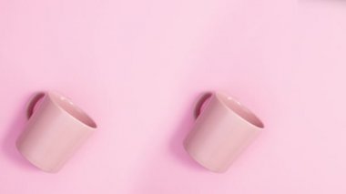 Çiçek çiçeği süslemesi pembe fincanda, pastel pembe arka planda. Hareketi durdur