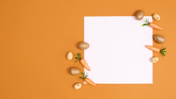 金蛋和胡萝卜在橙色背景的纸卡片上四处移动 停止运动最小平铺 — 图库视频影像