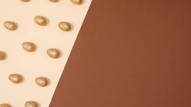 Çıplak kahverengi arka planda hareket eden parlak yumurtaların paskalya şablonu. Dur hareketi düz yatıyordu