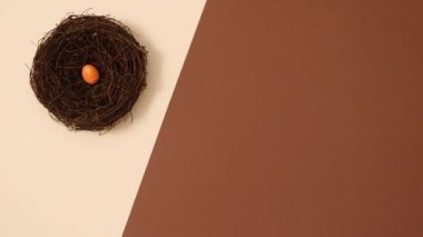 Turuncu ve sarı Paskalya yumurtaları çıplak kahverengi arka planda yuva yaparlar. Hareketi durdur