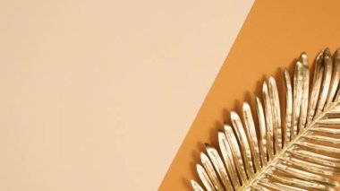 Turuncu çıplak arka planda altın renkli egzotik palmiye yaprağı görünüyor. Minimum düz tropik konsept. Hareketi durdur