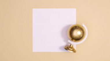 Modern altın küre çıplak arka planda kağıt kart üzerinde dönüyor. Dur hareketi düz yatıyordu