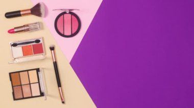 Mor pastel pembe ve bej arkaplan üzerine makyaj ürünlerinin minimum düzlem düzeni. Hareketi durdur