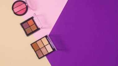 Göz farı paletleri ve fırçalar mor, pastel pembe ve bej arkaplanda görünür. Hareketi durdur