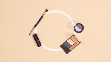 Paletler, fırçalar ve rujlar bej arka planda fotokopi alanı için daireler çizer. Hareketi durdur 