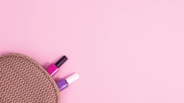 Manikür aletleri, pastel pembe arka planda setten görünür. Dur hareketi düz yatıyordu