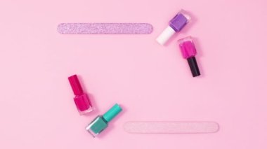 Parlak pembe arka planda tırnak cilası şişeleri ve dosyalardan oluşan yaratıcı bir kopya alanı çerçevesi. Hareketi durdur