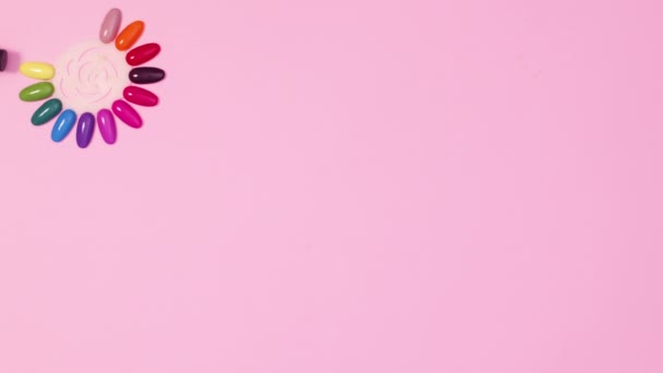 Бутылки Лак Ногтей Появляются Вокруг Образцов Цвета Ногтей Розовом Фоне — стоковое видео