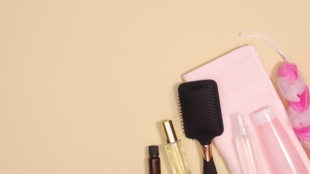 Na béžovém pozadí se objevují kosmetické výrobky pro péči o pleť s pastelově růžovým ručníkem. Stop motion flat lay