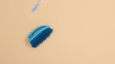 Mavi ev temizlik aletleri bej arka planda desen oluşturuyor. Hareketi durdur