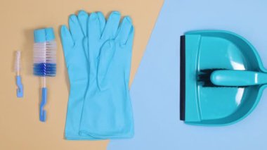 Mavi eldivenler, temizlik fırçaları ve ev aletleri mavi bej arka planda yanıp sönüyor. Dur hareketi düz yatıyordu