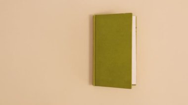 Parlak yeşil kapaklı klasik kitap bej arka planda kopya alanı ile görünür ve açılır. Dur hareketi düz yatıyordu