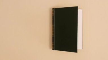 Koyu yeşil ciltli klasik kitap, bej arka planda fotokopi alanı ile görünür ve açılır. Dur hareketi düz yatıyordu