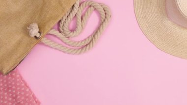 Yaz plajı aksesuarları ve hasır çanta ve şapka pastel pembe arka planda görünür. Hareketi durdur