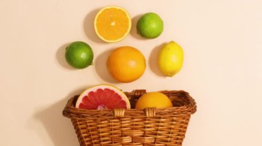 Wooden basket appear on beige background and fresh citrus fruits appear. Stop motion