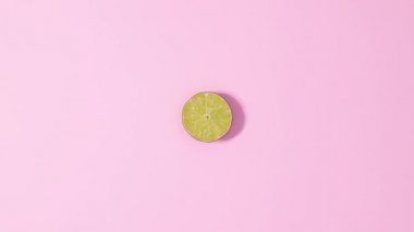 Citrus lime fruit rotating on  pastel pink background. Stop motion