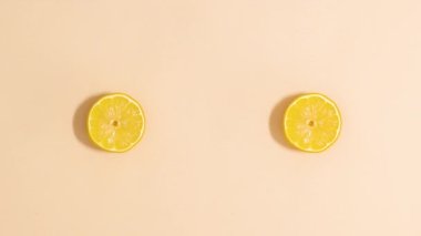 Making two creative summer yellow flowers made of lemon and flower petals on beige background. Stop motion flat lay