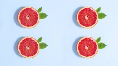 Four citrus grapefruits rotating with green leaves on bright blue background. Stop motion