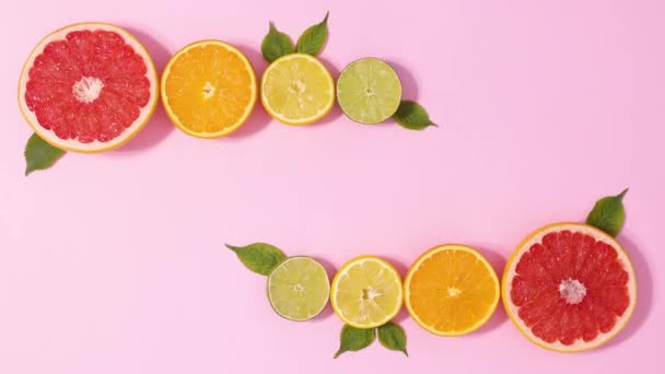 Sliced Fresh Citrus Fruits Arrangement Green Leaves Move Pastel Pink — Vídeo de stock