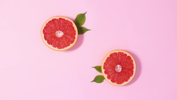 Two Sliced Fresh Grapefruits Green Leaves Move Pastel Pink Background — Video Stock