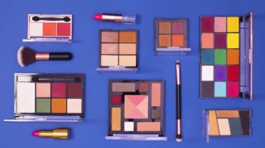 Makyaj ürünleri koyu mavi arka planda desen oluşturur. Dur hareketi düz yatıyordu