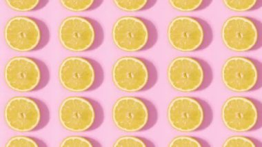 Pastel pembe arka planda dönen dilimlenmiş turunçgil limonlarından yapılmış bir desen. Dur hareketi düz yatıyordu