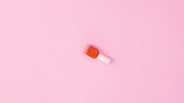 Manikür cilası şişesi pastel pembe arka planda dönüyor. Dur hareketi düz yatıyordu