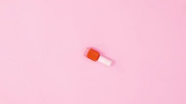 Manikür ojeli şişeler dönüyor ve pastel pembe arka planda renk değiştiriyor. Hareketi durdur