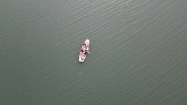 Motorlu teknesi gölde bozulduğu için çocuk elleriyle kürek çekiyor. hava görünümü 