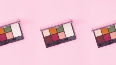 Parlak pembe arka planda dönen üç renkli göz farı paleti. Hareketi durdur