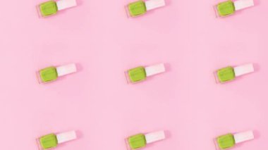 Tırnak cilası şişeleri pastel pembe arka planda döner. Hareketi durdur