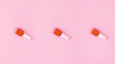 Tırnak cilası şişeleri pastel pembe arka planda döner. Hareketi durdur