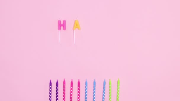 生日快乐停止运动 色彩艳丽的蜡烛和生日祝福的蜡烛出现在粉红的主题上 — 图库视频影像