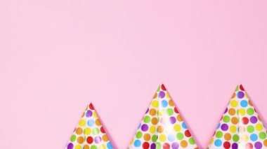 Pastel pembe temanın altında parti şapkaları ve pembe kurdeleler görünür. Hareketi durdur