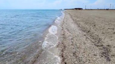 Güneşli yaz gününde kumlu sahile vuran deniz dalgaları üzerinde yakın uçuş. Hava görünümü 