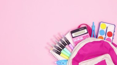 Okul gereçleriyle dolu sırt çantası pastel pembe temanın sağ tarafında görünüyor. Hareketi durdur 