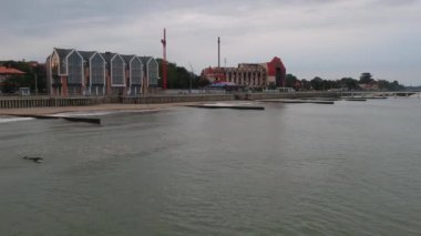 Bir sörfçünün ve Zelenogradsk şehir rıhtımının bulutlu bir günde gökyüzünde uçan insansız hava aracının görüntüsü.