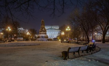 Gece karlı meydanda bir anıt.