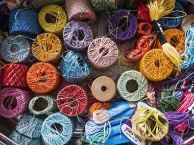 Çeşitli uzunluk ve kalınlıkta ipliklerle bir dikiş kutusunda bir dizi renk..