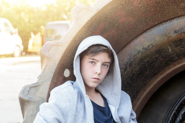 Portret nastoletniego chłopca opierając się ogromne opony — Zdjęcie stockowe