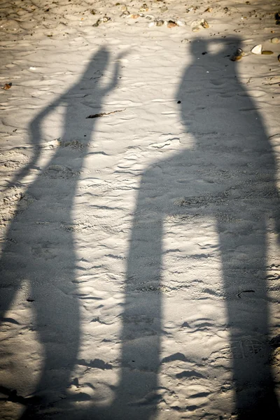 Dancing shadows of two persons at the beach — Stock Photo, Image