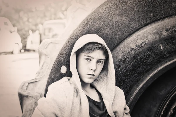 Портрет хлопчика-підлітка, що спирається на величезну шину — стокове фото