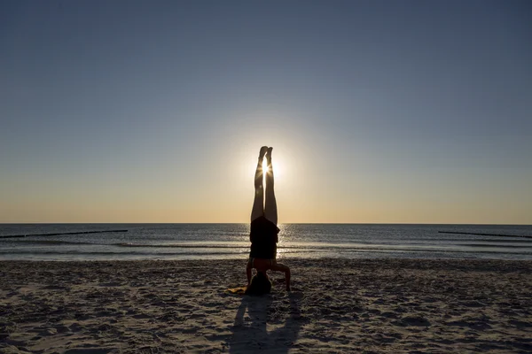 Junge Frau steht auf ihren Händen am Strand. — Stockfoto