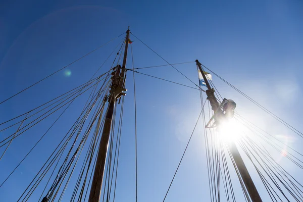 Mastro do navio, céu azul, sol e bandeiras — Fotografia de Stock