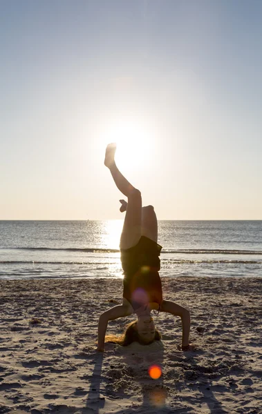 Junge Frau steht auf ihren Händen am Strand. — Stockfoto