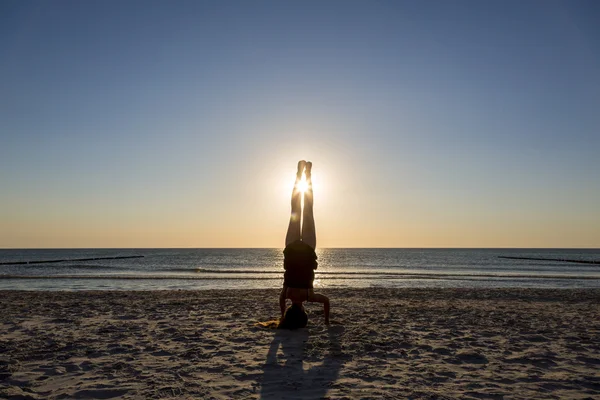 Junge Frau steht auf ihren Händen am Strand. — Stockfoto