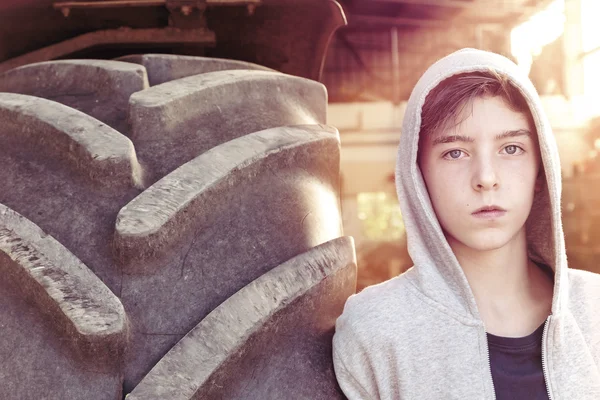 Portrait of a teenage boy leaning against a huge tire — Stock Photo, Image