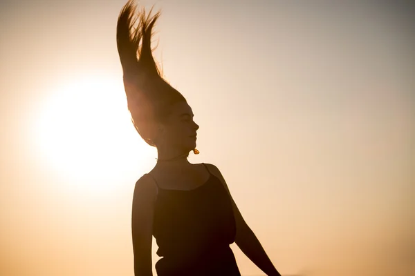 सूर्यास्त आणि हालचालीत एक किशोरवयीन मुलगी सिल्हूट — स्टॉक फोटो, इमेज