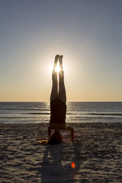 Giovane donna in piedi sulle sue mani in spiaggia . — Foto Stock
